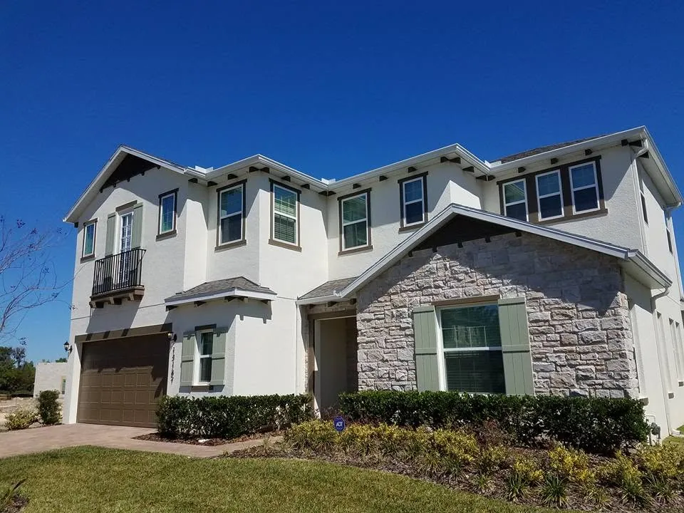 White stucco two story stone gable sage shutters juliet balcony seamless gutters